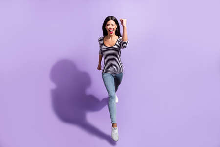 Full size photo of young happy positive smiling woman running fast speed in air isolated on purple color backgroundの写真素材
