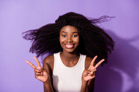 Portrait of charming cheerful dark skin person two arms fingers show v-sign isolated on purple color backgroundの写真素材