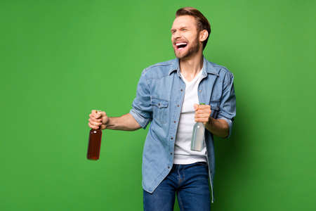 Photo portrait of laughing man keeping beer glass bottles inviting to party isolated vivid green...