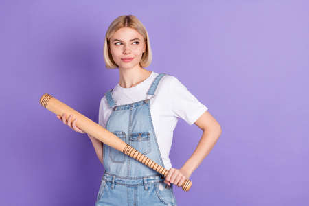 Photo of nice optimistic short hairdo blond lady hold bat look empty space wear white t-shirt isolated on violet backgroundの写真素材