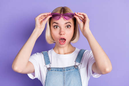Photo of nice impressed short hairdo blond lady wear spectacles white t-shirt isolated on violet...