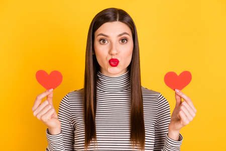 Photo of lovely young woman hold hands small red paper heart shapes isolated on bright yellow color backgroundの写真素材