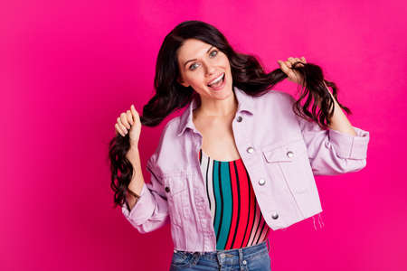 Photo of optimistic brunette cute lady hold hair wear light jacket isolated on vibrant pink color backgroundの写真素材