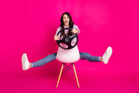 Full size photo of impressed brunette nice lady sit drive wear jacket jeans sneakers isolated on pink backgroundの写真素材