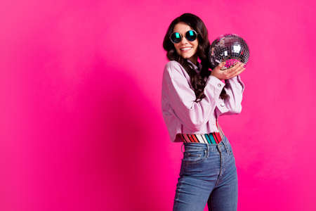 Photo of optimistic brunette lady hold ball look empty space wear spectacles top jeans jacket isolated on pink backgroundの写真素材