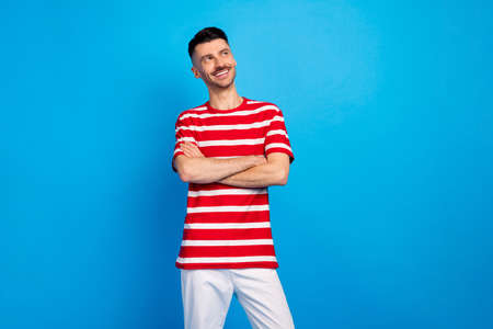 Photo of happy charming cheerful guy hold arms crossed look empty space isolated on pastel blue color backgroundの写真素材