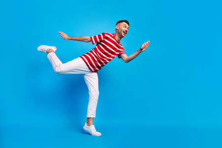 Low angle view profile side full size photo of funny man look empty space dance isolated on blue color backgroundの写真素材
