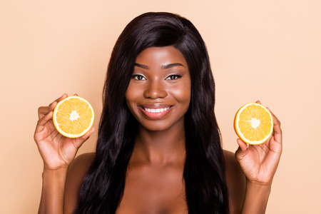 Photo of positive pretty lady presenting two orange slices look camera beaming smile isolated beige backgroundの写真素材