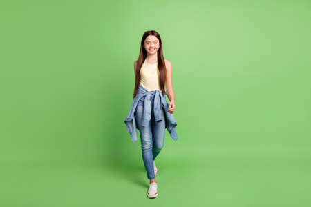 Full length photo of young excited girl happy positive smile confident go walk step isolated over green color backgroundの写真素材