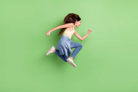 Full size profile side photo of happy excited crazy cheerful girl jumping look copyspace isolated on green color backgroundの写真素材