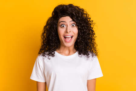 Photo of young happy excited crazy shocked amazed surprised girl sees big sale discount isolated on yellow color backgroundの写真素材