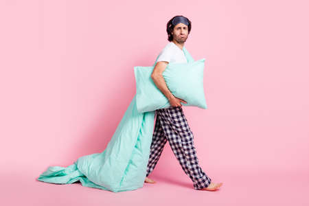Full size photo of young funky crazy man unhappy with early morning hold pillow blanket isolated on pink color backgroundの写真素材