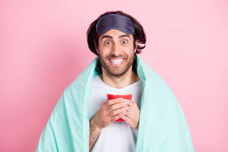 Photo of young happy funky smiling cheerful crazy man covered in blanket drink morning tea isolated on pink color backgroundの写真素材