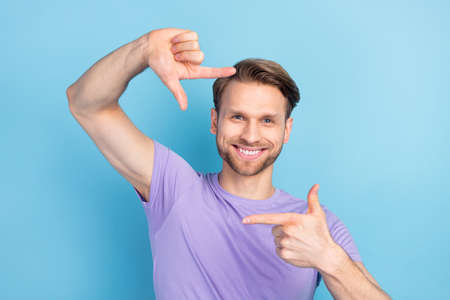 Photo portrait of guy keeping frame with fingers taking photo isolated on pastel blue color...