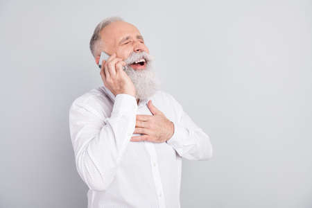 Photo of happy charming joyful old man hold phone call talk laugh joke isolated on grey color...