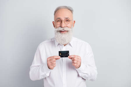 Photo of aged business man happy positive smile hold credit card income profit customer isolated over grey color backgroundの写真素材