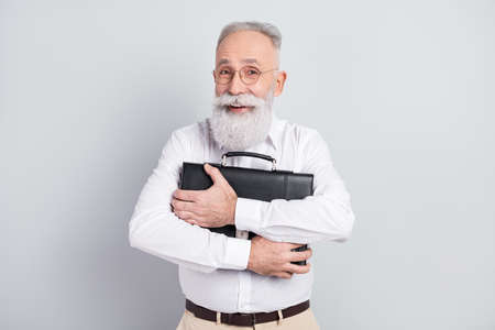 Photo of happy cheerful attractive positive old man hug embrace briefcase isolated on grey color backgroundの写真素材
