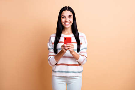 Photo of young attractive girl happy positive smile use cellphone chat type sms isolated over beige...