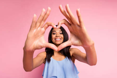 Photo of optimistic nice brunette lady show heart wear blue top isolated on pastel pink color...