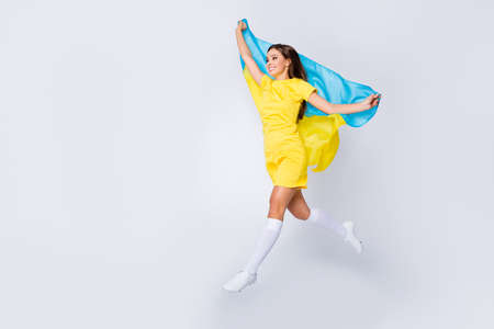 Full length body size view of nice beautiful dreamy cheerful cheery straight-haired girl jumping going holding in hands Ukrainian flag liberty day isolated on light white gray pastel color backgroundの写真素材