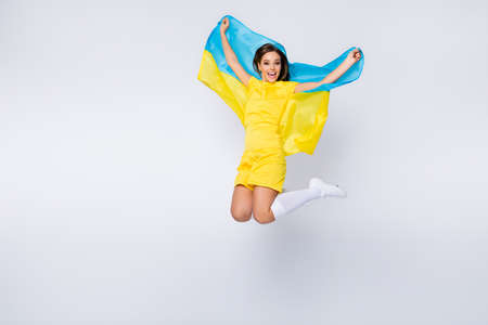Full length body size view of nice beautiful lovely glad cheerful cheery straight-haired girl jumping holding in hands Ukrainian flag having fun isolated over light white gray pastel color backgroundの写真素材