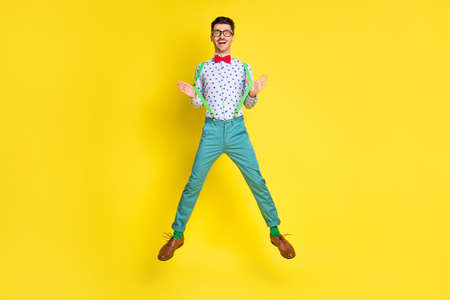Full size photo of young excited man happy positive smile have fun jump up isolated over yellow color background.の写真素材