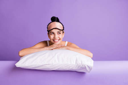 Photo portrait of cute girl laying on pillow dreaming looking copyspace smiling isolated on pastel violet color backgroundの写真素材