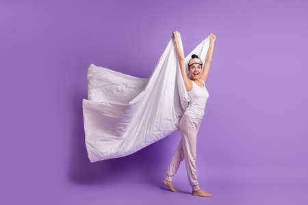 Full length body size photo of girl on pajama party keeping white blanket childish playful isolated pastel purple color backgroundの写真素材