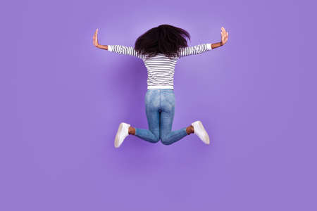Full body back photo of cool millennial lady jump wear pullover jeans isolated on violet color backgroundの写真素材