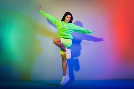 Full length body size view of pretty cheerful girl jumping good mood rest isolated over multicolor vivid neon light backgroundの写真素材