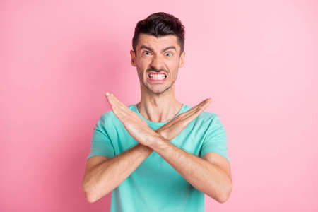 Photo of young unhappy angry aggressive displeased stressed man showing no sign isolated on pink color backgroundの写真素材