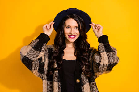 Photo of charming young lady toothy beaming smile wear black hat plaid coat isolated yellow color backgroundの写真素材