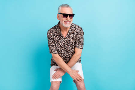 Photo of funky positive happy old man dance wear sunglass free time weekend isolated on blue color...