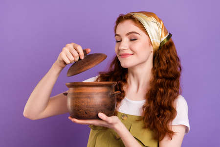 Portrait of attractive dreamy cheery girl preparing soup smelling isolated over violet purple color backgroundの写真素材