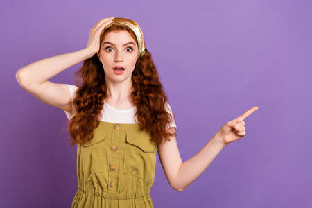 Photo of amazed shocked young astonished lady point finger empty space hand head isolated on purple...
