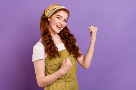 Photo of cheerful nice pretty ginger woman raise fists good mood winner isolated on purple violet color backgroundの写真素材