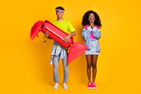 Full length body size view of funky cheerful couple holding in hands large fake candy isolated on bright yellow color backgroundの写真素材