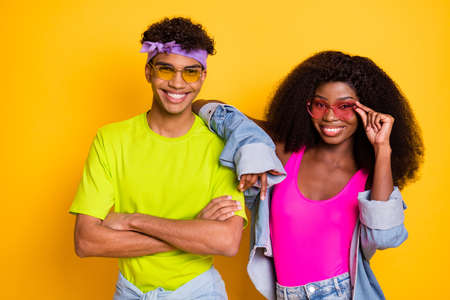Photo of cute pretty young people wear jeans clothes arm dark glasses isolated yellow color...