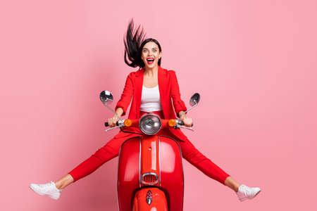 Full length photo of young attractive girl happy positive smile have fun crazy ride motorbike isolated over pink color backgroundの写真素材