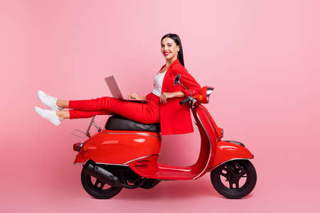Full length profile side photo of young girl happy positive smile sit bike type email laptop isolated over pink color backgroundの写真素材