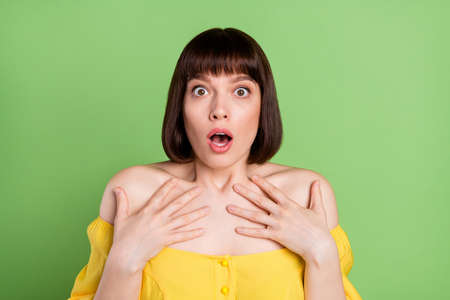 Photo of shocked astonished young woman hold hands point herself question isolated on green color backgroundの写真素材