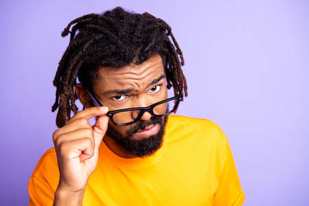 Portrait of nice serious brunette hairdo guy touch spectacles wear orange t-shirt isolated on lilac color backgroundの写真素材