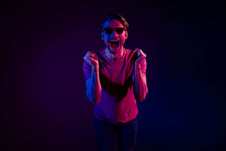 Portrait of attractive cheerful amazed delighted funny guy having fun rejoicing isolated over dark neon purple color backgroundの写真素材
