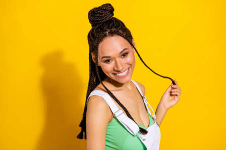 Photo of excited charming dark skin woman dressed white overall arm braid smiling isolated yellow...