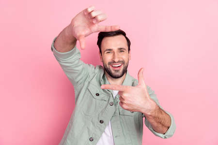 Photo of nice optimistic brunet man make photo wear grey shirt isolated on pastel pink color backgroundの写真素材