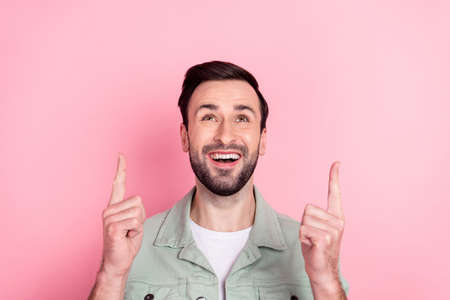 Photo of nice optimistic brunet man point look up wear grey shirt isolated on pastel pink color backgroundの写真素材