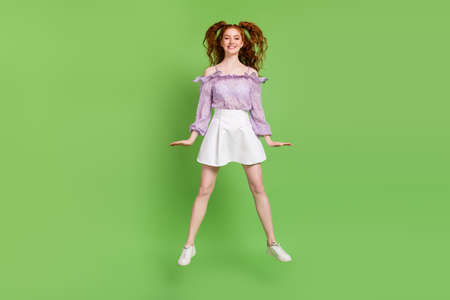 Full length photo of funky orange hairstyle millennial lady jump wear blouse spectacles skirt isolated on green color backgroundの写真素材