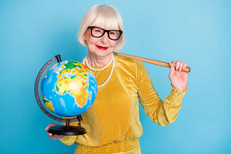 Photo of cheerful short hairdo aged lady hold stick globe wear eyewear blouse isolated on blue color backgroundの写真素材