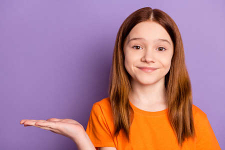 Portrait of attractive cheery cute girl holding on palm copy empty blank space isolated over violet purple color backgroundの写真素材