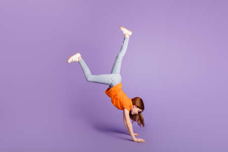 Full length body size view of attractive flexible girl standing walking on hands having fun isolated over violet purple color backgroundの写真素材